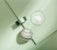 BABOR Gesichtscreme in einem offenen Tiegel mit Cremetextur auf grünem Hintergrund.