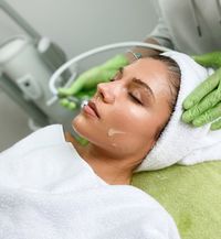 Frau erhält eine professionelle Gesichtsbehandlung mit Pflegeprodukt in einem Kosmetikstudio.